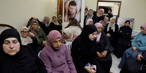 Frauen versammeln sich in einem Zimmer, an der Wand ein Bild von Khader Adnan