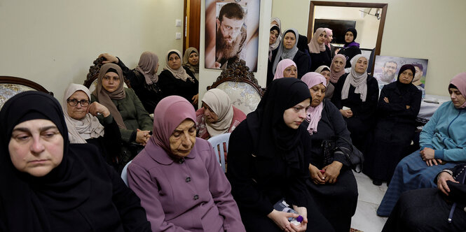 Frauen versammeln sich in einem Zimmer, an der Wand ein Bild von Khader Adnan