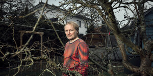 Der Autor Jochen Schmidt im Garten hinter einem Baum