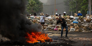 Pressefotograf nimmt ein Feuer ins Visier vor einer Barrikade des antidiktatorischen Widerstands am 30. März 2021 in Yangon