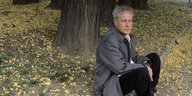 Der Autor Dennis Cooper sitzt im Wald und blickt in die Kamera