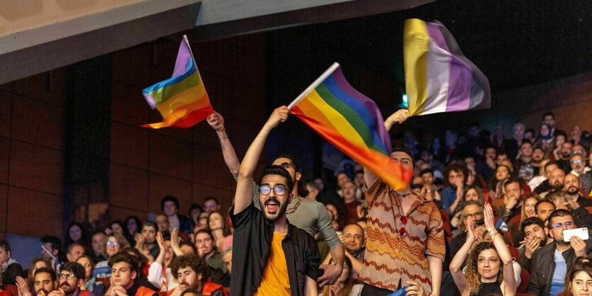 Begeisterte Anhänger der TIP Partei schwenken Regenbogenfahnen in einem Saal