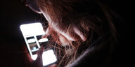 Person im Dunkeln guckt auf ein hell leuchtendes Smartphone