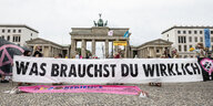 Transparent einer Demo vor dem Brandenburger Tor. Aufschrift: "Was brauchst du wirklich?"