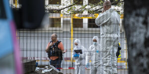 Polizisten stehen hinter einem Zaun