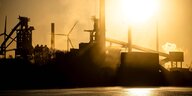 Das Bremer Stahlwerk, von der gegenüberliegenden Weserseite aus gesehen, von Sonne beglänzt: Mit Milliarden fördert Bremen die Umstellung auf Wasserstoff-Öfen
