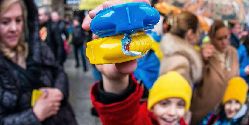 Ein ukrainischer Junge in München zeigt seinen blau-gelben Kaugummispender in den Farben der ukrainischen Flagge.