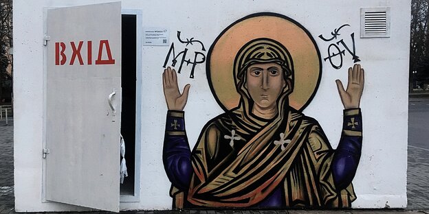 Eine weisse Box mit einer geöffneten Tür und einem Graffity dass eine Jesus Figur zeigt