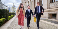 Drei junge Aktivist:innen von der "Letzten Generation" laufen über Kopfsteinpflaster. Sie sind auf dem Weg zu Bundesverkehrsminister Volker Wissing