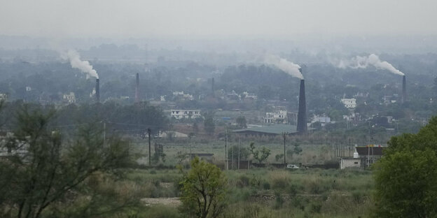 Rauch steigt aus Schornsteinen einer Ziegelsteinfabrik in Jammu im Norden Indiens in einen grauen Himmel auf.