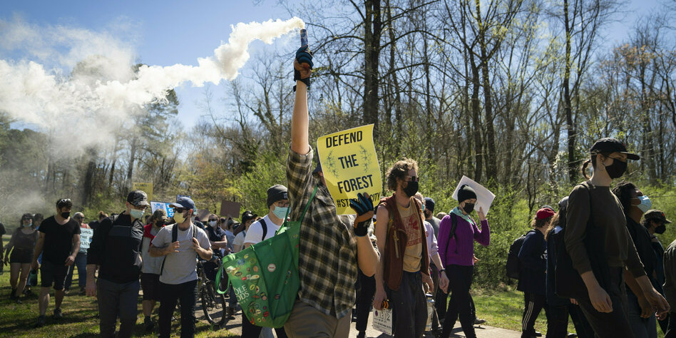 Menschen protestieren mit Plakaten und laufen durch den Wald