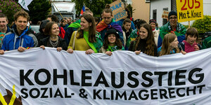 Eine Gruppe vor allem junger Menschen läuft mit einem Transparent, auf dem "Kohleausstieg Sozial & Klimagerecht. Für eine Lausitz mit Zukunft!" steht.