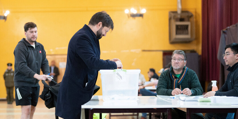 Eine Person steht vor einer Wahlurne