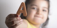 Ein kleines Mädchen zeigt den Buchstaben A