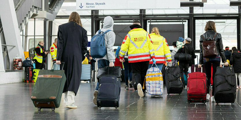 Menschen mit Rpllkoffern in einem Bahnhof