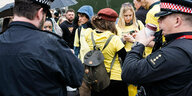 Polizisten stehen um Demonstranten mit gelben Hemden herum