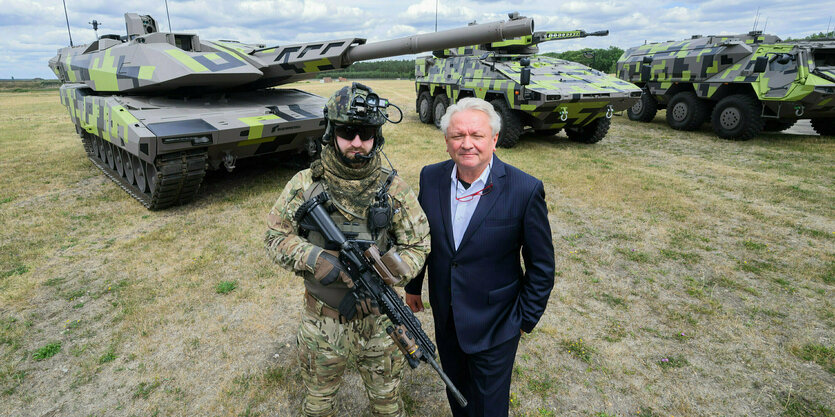 Armin Papperger posiert mit einem Soldaten vor Panzern