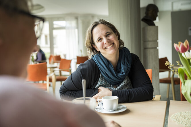 Die Seniorenberaterin Christine Nawrath spricht mit einer Bewohnerin und lächelt diese freundlich an