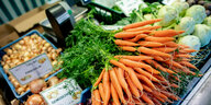 Karotten und Zwiebeln stehen an einem Obst- und Gemüsestand auf einem Wochenmarkt zum Verkauf
