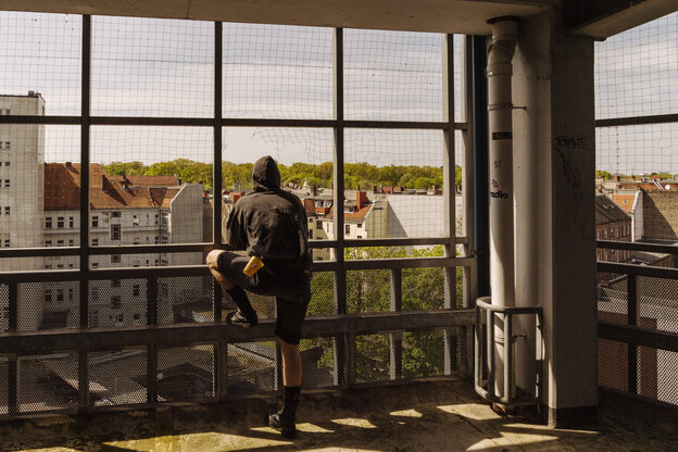 Ein Mann von hinten blickt aus einem Parkhaus ins Grün Ein Mann von hinten blickt aus einem Parkhaus ins Grün