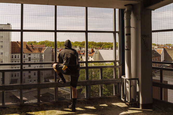 Ein Mann von hinten blickt aus einem Parkhaus ins Grün