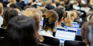 Studentinnen und Studenten sitzen während einer Vorlesung in einem Hörsaal