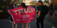 Zwei junge Frauen zeigen eine Fahne mit der Aufschrift "Trump 2024 - Make America Great Again"