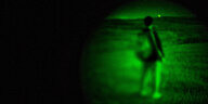 Eine Person mit Rucksack im Bild eines Nachtsichtgerätes