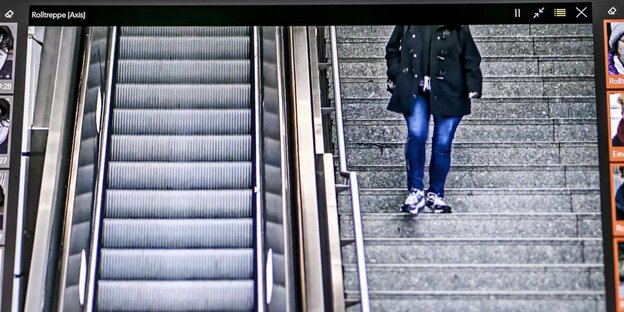 Das Bild einer Überwachungskamera zeigt eine Person auf einer Treppe, daneben eine Rolltreppe