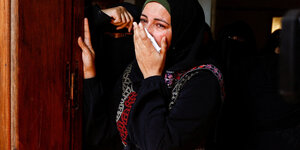 Eine weinende Frau hält sich ein Tuch vor Mund und Nase