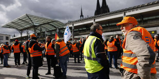 Menschen in Warnwesten auf einem Bahnsteig