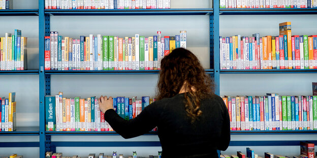 Eine Mitarbeiterin sortiert in der zentralen Stadtbibliothek in der Südstadt von Hannover ein Regal mit Reiseführern