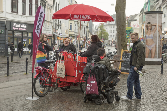 Infostand der Linkspartei mit rotem Schirm