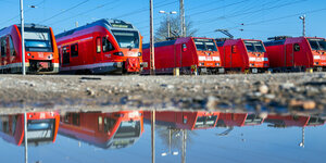 Personenzüge der Deutschen Bahn stehen auf Abstellgleisen und spiegeln sich in einer Pfütze