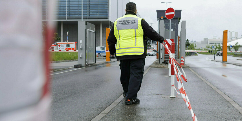 Eine Person mit gelber Weste hält ein Absperrband