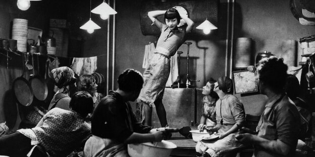 Anna May Wong als Shosho auf einem Küchentisch tanzend, umgeben von Küchenpersonal
