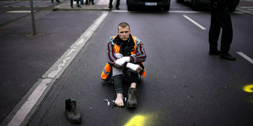 Ein Kimaaktivist sitzend auf der Straße