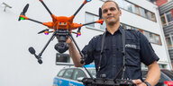 Drohnenpilot Thomas Müller mit einer orangefarbenen Polizei-Drohne bei einer Vorführung der niedersächsischen Polizei.