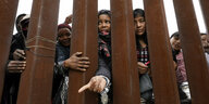 Frauen stehen hinter der Grenzmauer zwischen Mexico und den USA