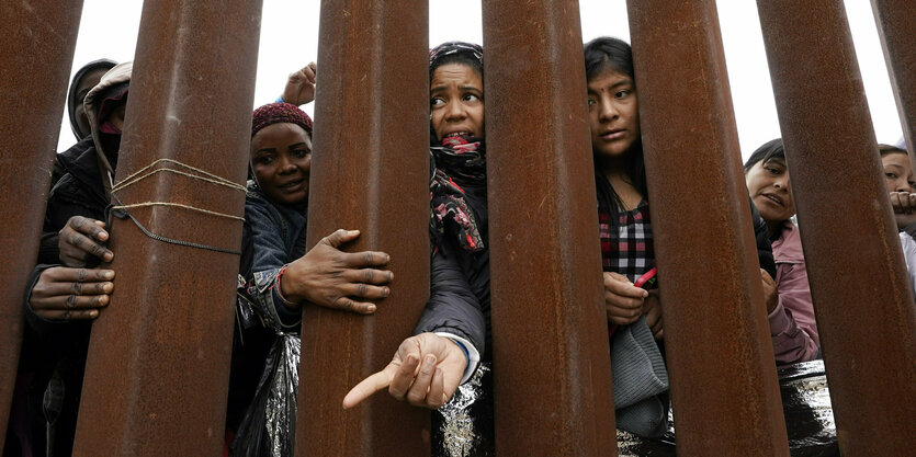 Frauen stehen hinter der Grenzmauer zwischen Mexico und den USA