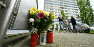 Blumen und Kerzen stehen vor dem Hochhaus in Ratingen, wo bei einem Einsatz Polizei- und Feuerwehrleute schwer verletzt wurden.