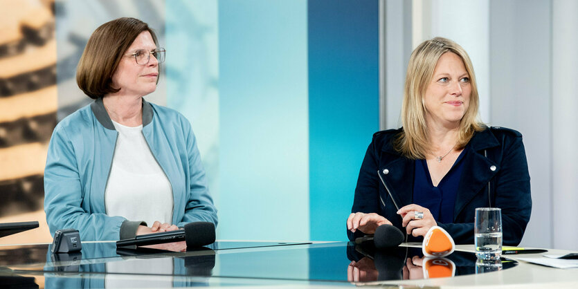 Zwei Frauen an einem Tisch, sie schauen beide nach rechts