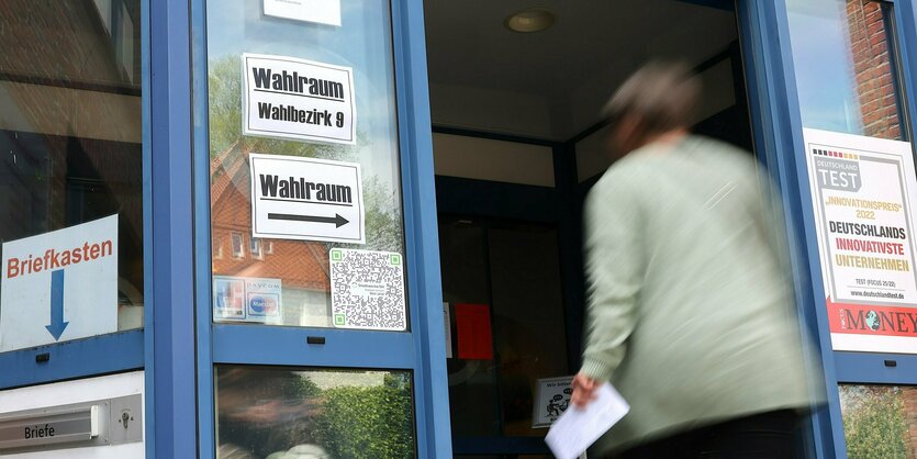 Eine Frau betritt einen Wahlraum, um ihre Stimme abzugeben.