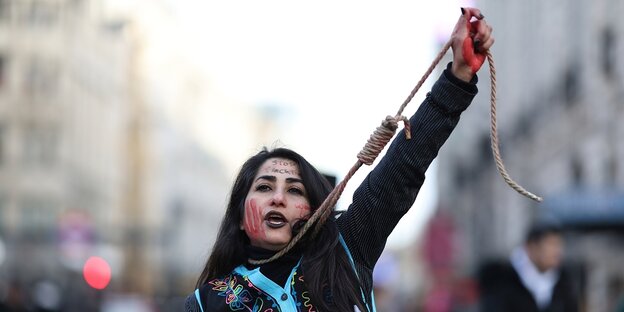 Eine Frau hat sich einen Strick um den Hals gebunden und protestiert so gegen die Todesstrafe im iran