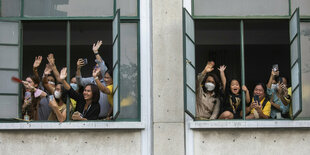 Menschen winken frühlich aus einem Fenster