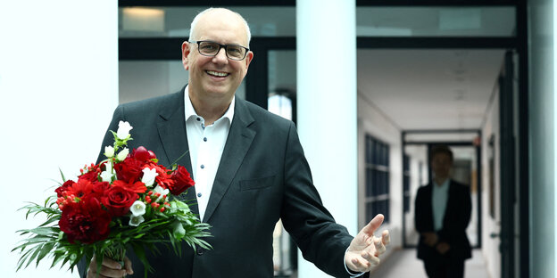 Andreas Bovenschulte mit geöffnetem Arm und einem Blumenstrauß