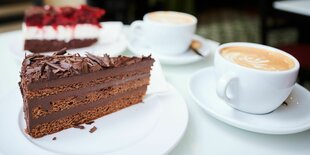 Auf einem Tisch stehen zwei Stück Torte und Cappuccino