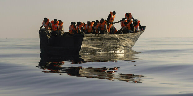Menschen in einem Boot mit Rettungswesten auf hoher See