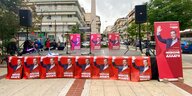 rote Wahlplakate mit einem Männergesicht stehen auf einem Platz