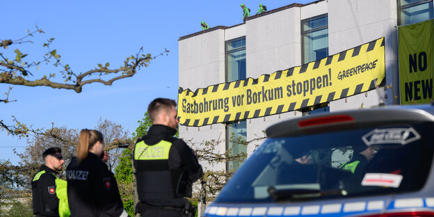 Greenpeace-Aktivisten stehen auf dem Dach des niedersächsischen Landtages und haben ein Banner mit der Aufschrift "Gasbohrung vor Borkum stoppen" herab gelassen, vor dem Gebäude stehen mehrere Polizeiwagen und Beamte..